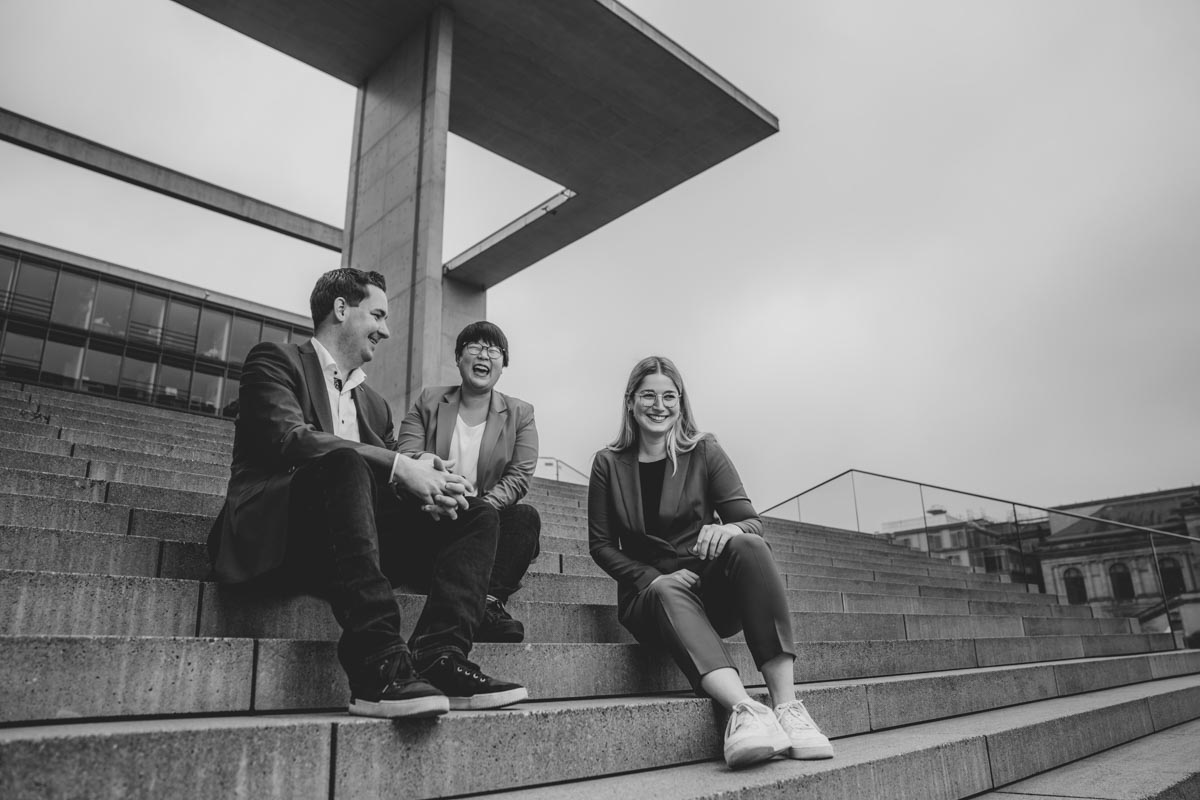 Brian Nickholz, Ye-One Rhie und Lena Werner auf den Stufen des Marie Elisabeth Lüders Hauses im Regierungsviertel Berlin